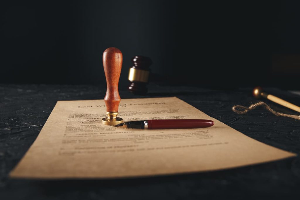 Protecting Your Assets: The Importance of a Properly Notarized Last Will and Testament 4 Last will and testament document with notary seal stamp and pen on a dark table, highlighting the importance of legal notarization for estate planning.