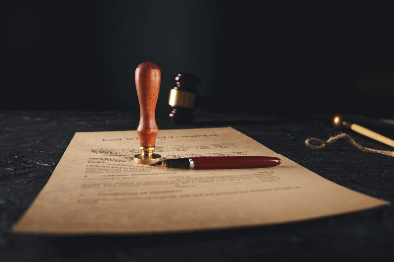 Protecting Your Assets: The Importance of a Properly Notarized Last Will and Testament 1 Last will and testament document with notary seal stamp and pen on a dark table, highlighting the importance of legal notarization for estate planning.