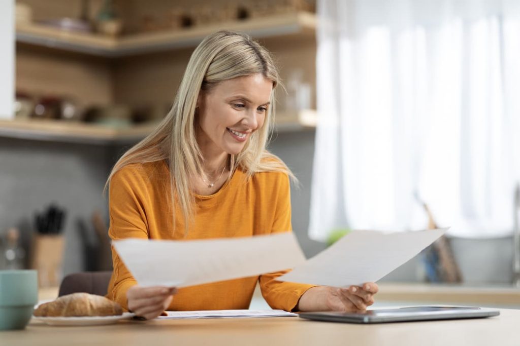 The Proof of Settlement: Everything You Need to Know 7 Smiling woman reviewing official documents at home – understanding proof of settlement and getting it notarized or Apostilled with NotaryPublic24.com