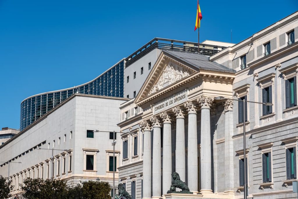 The Certificate of No Impediment (CNI): A Comprehensive Guide to International Marriages 2 Front view of the Spanish Congress of Deputies building in Madrid under a clear blue sky, symbolizing official processes such as obtaining a Certificate of No Impediment (CNI) for international marriage – relevant to notarial and legalization services at NotaryPublic24.com.